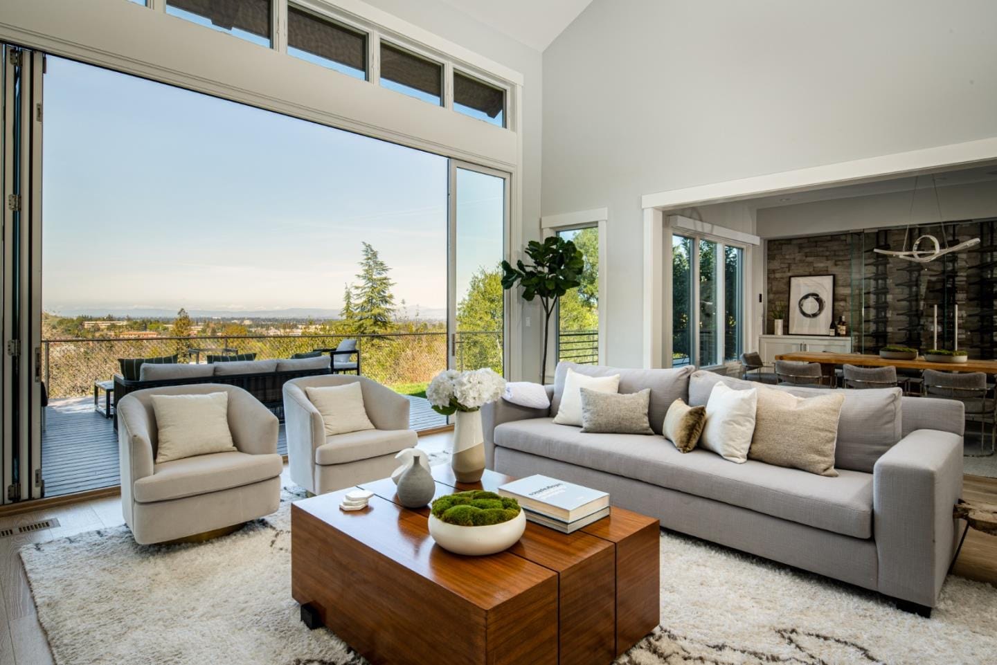 A staged living room opening onto a valley view through full-height glass